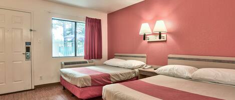 Une chambre d’hôtel avec deux lits, une fenêtre avec des rideaux, une lampe fixée au mur et une porte.
