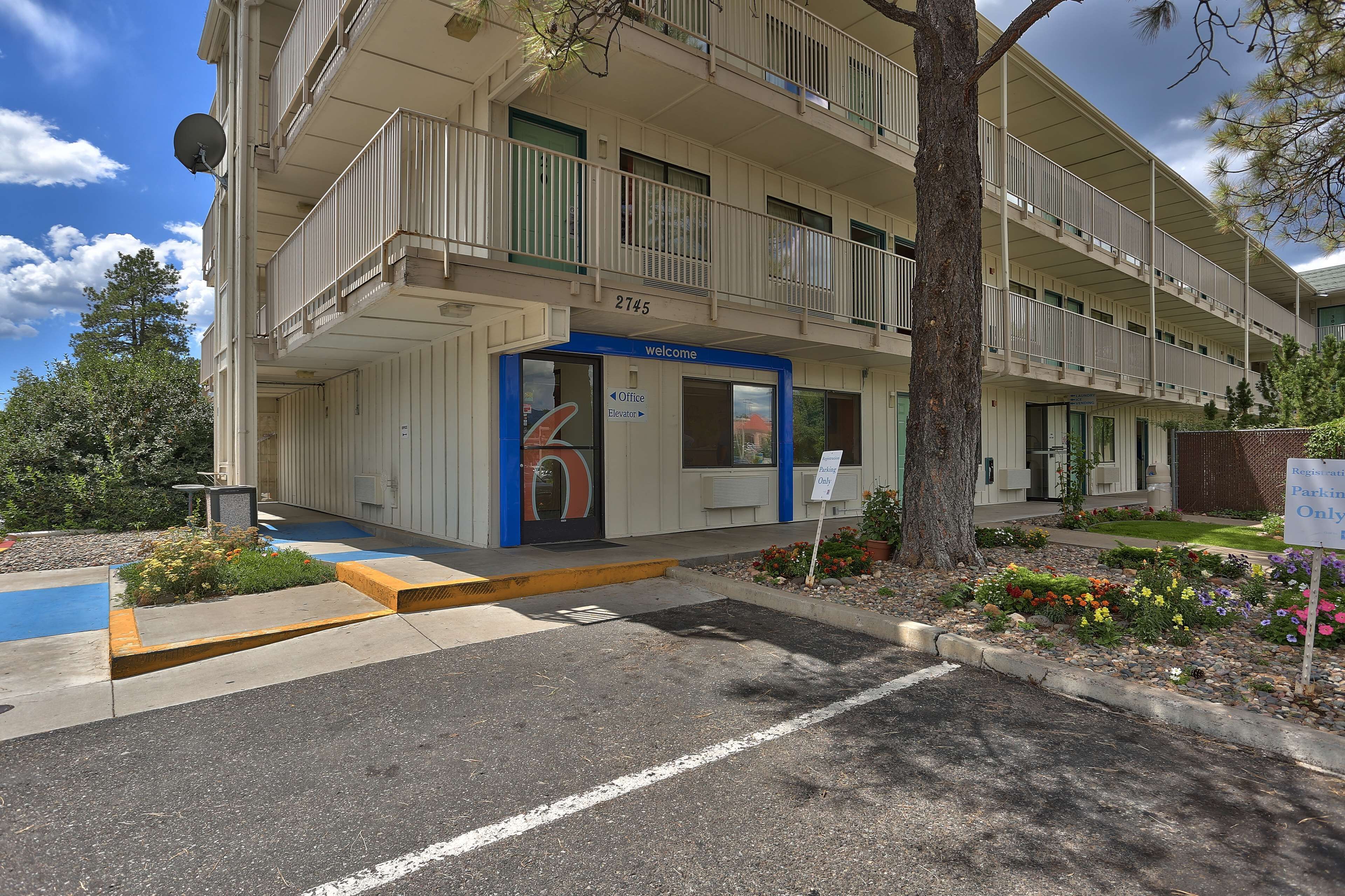 A multi-story building with a balcony, a welcome sign, and a parking sign.