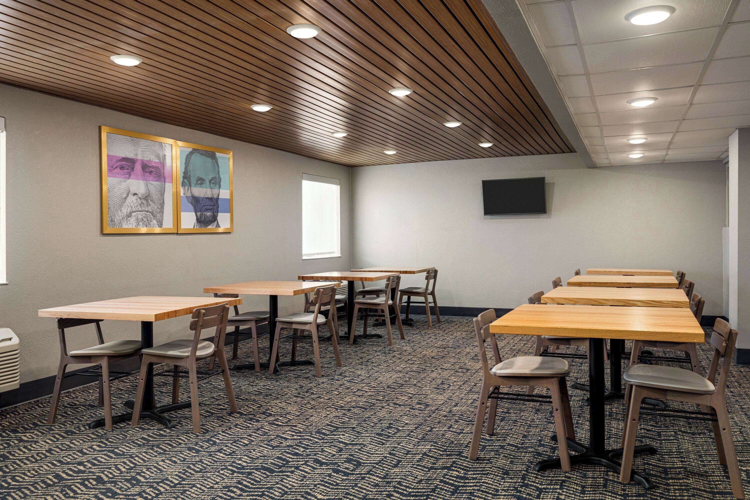 A conference room with wooden tables and chairs, a patterned carpet, and a ceiling with recessed lighting.
