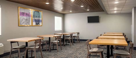 A conference room with wooden tables and chairs, a patterned carpet, and a ceiling with recessed lighting.