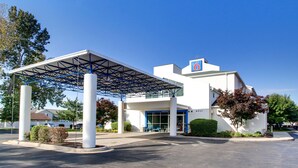 A modern hotel with a covered entrance, a prominent '6' sign, and a welcoming 'welcome' sign. - Motel 6 Springfield, IL (Springfield)