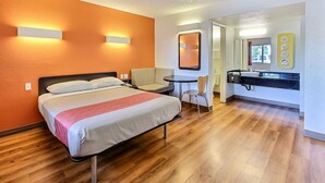 A hotel room with a bed, a desk, and a bathroom with a sink and mirror. - Motel 6 Campbell, CA - San Jose (Campbell)