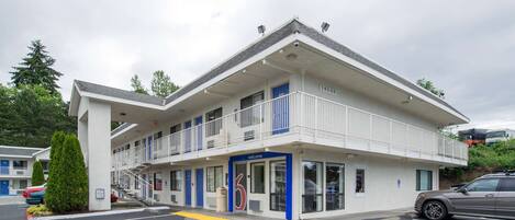 Un motel con entrada azul, balcón y estacionamiento.
