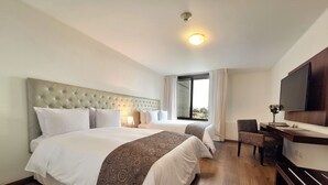 A hotel room with two beds, a desk, a chair, a TV, and a window with curtains. - NM Lima Hotel (Lima)