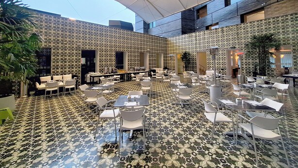 A spacious indoor area with patterned flooring, multiple tables and chairs, and a high ceiling with a large canopy. - NM Lima Hotel (Lima)
