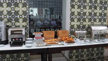 A buffet setup with various food items, a coffee machine, and a toaster.