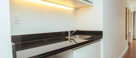 A modern kitchen with a black countertop, stainless steel sink, and white cabinets.