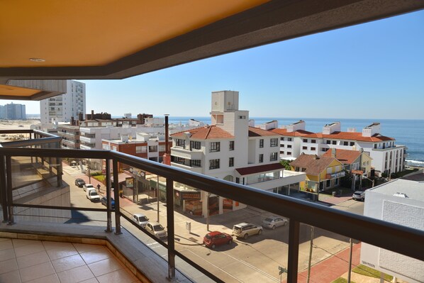 A balcony with a view of a coastal cityscape, including buildings and a clear sky.