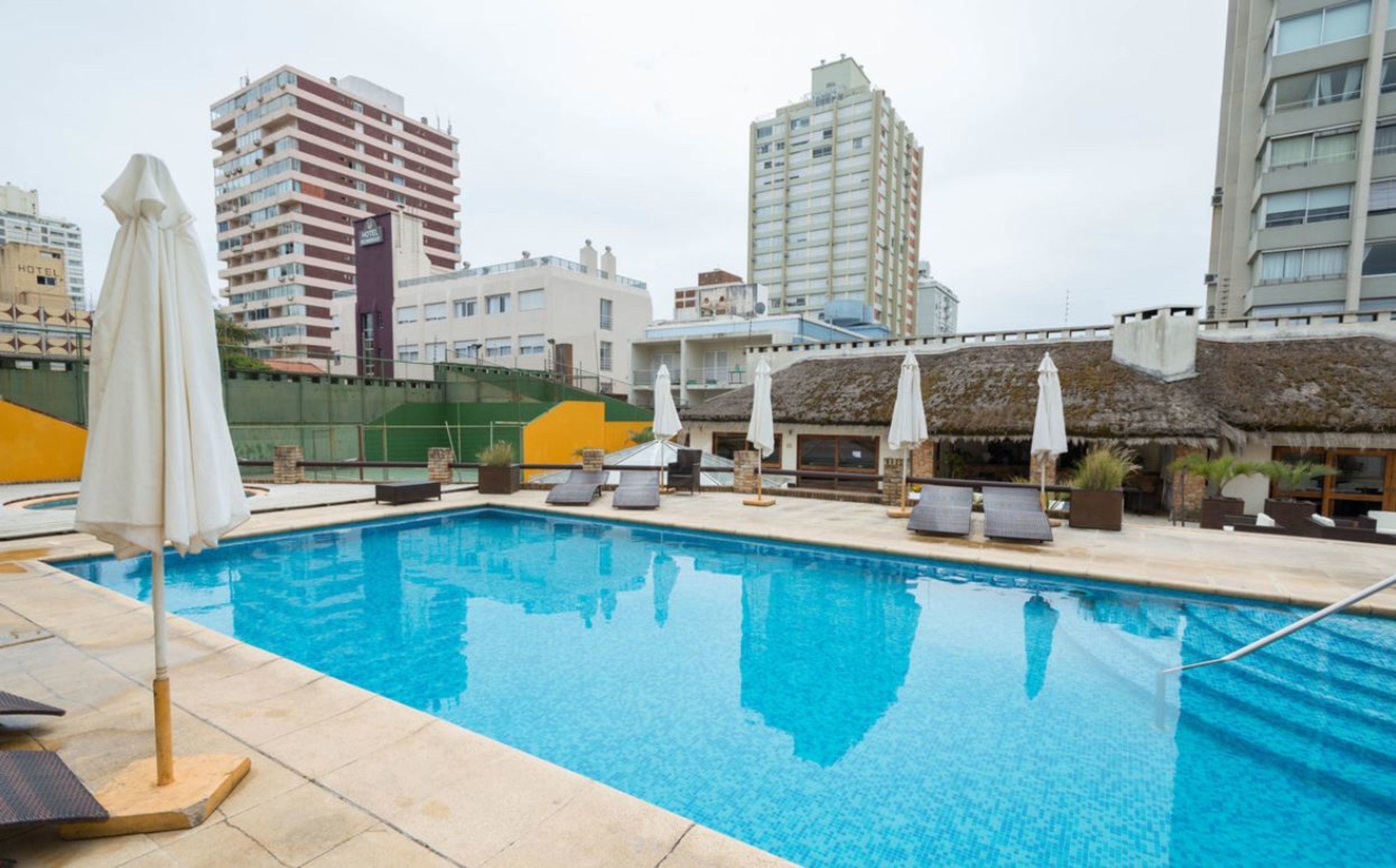 Una piscina techada, una piscina al aire libre, sombrillas
