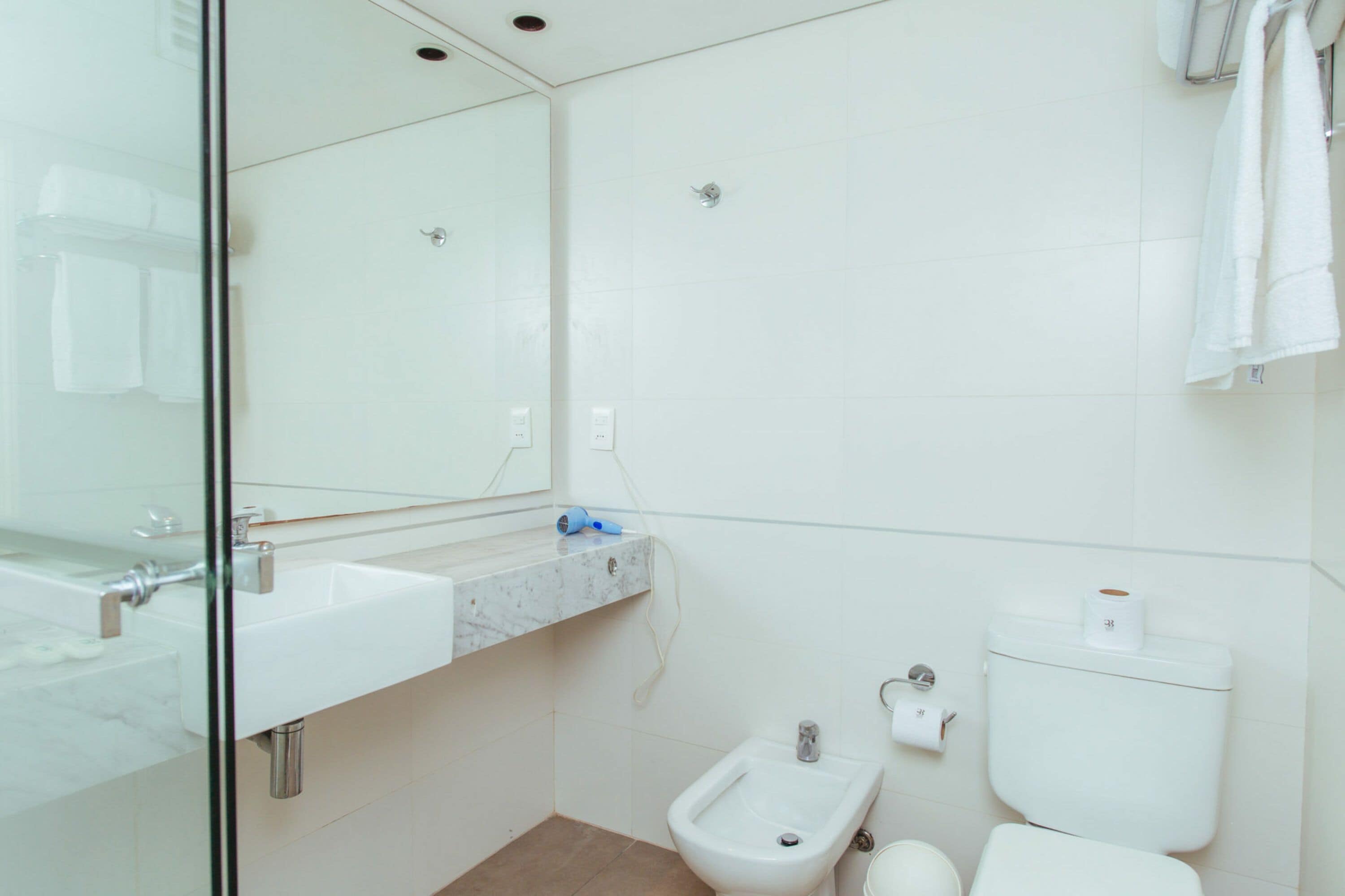 Un baño moderno con cabina de ducha de vidrio, lavamanos de mármol, un bidé y un inodoro.