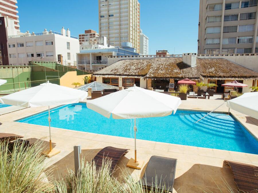 Una piscina techada, una piscina al aire libre, sombrillas