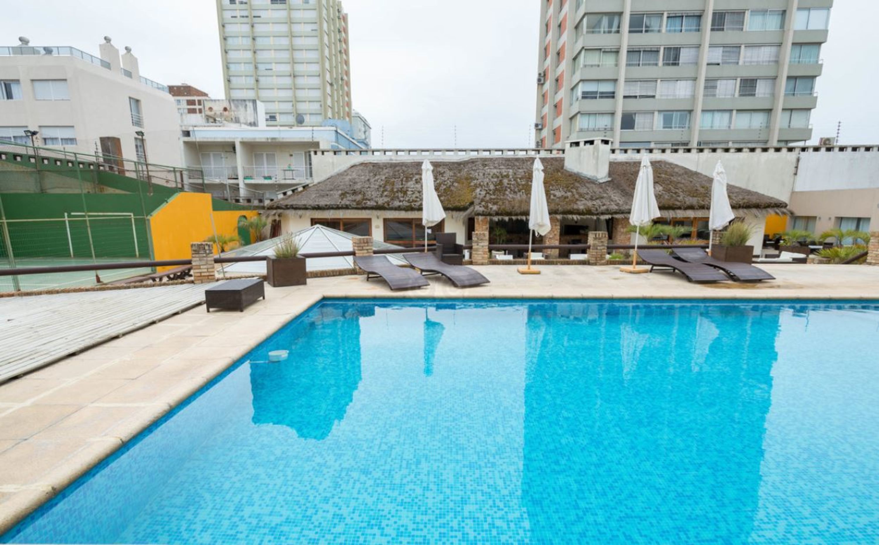 Una piscina techada, una piscina al aire libre, sombrillas