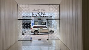 Ein Hotel Eingang mit modernem Design, einschließlich eines schmiedeeisernen Tores mit geometrischem Muster und freier Sicht auf ein geparktes Auto davor.