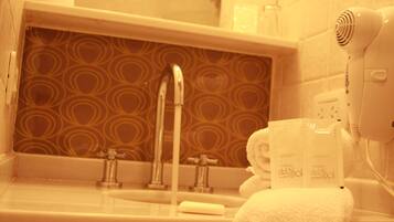 Un baño con pared estampada, un lavamanos, una toalla y un secador de pelo.