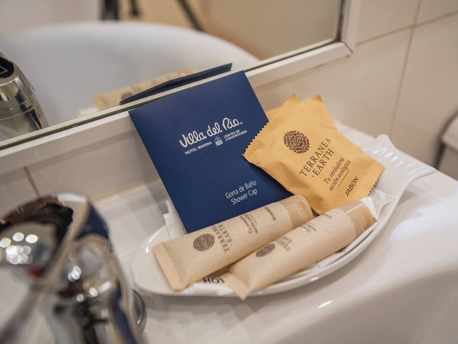 A bathroom counter with a blue booklet, a brown paper bag, and two rolled towels.