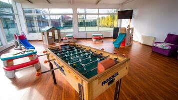 Relax and play in this spacious indoor play area featuring a foosball table, play structures, and a TV.