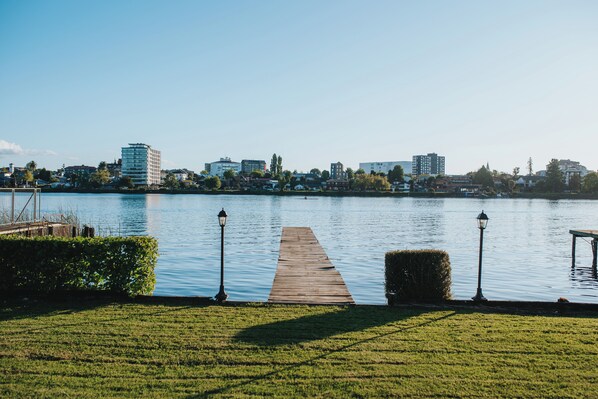 A wooden pier extending into a calm lake, surrounded by a well-maintained grassy area and a row of street lamps. - Hotel Marina Villa del Rio (Valdivia)