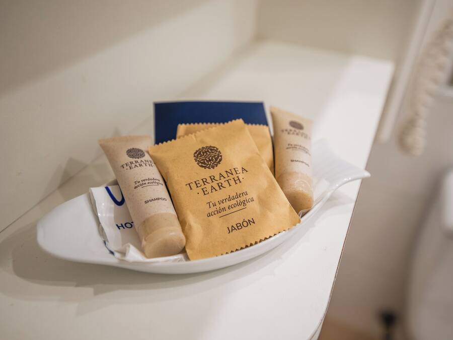 Un plato blanco con varias botellas de champú Terranova Earth y una caja azul sobre una encimera blanca.