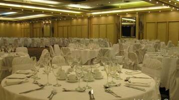 A banquet hall with round tables set for dining, featuring white tablecloths and glassware.