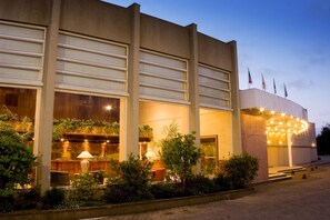 Welcome to our hotel, featuring a striking entrance with a curved facade surrounded by lush greenery.