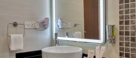 A bathroom with a large mirror, a white sink, and toiletries.