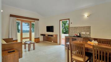Habitación de hotel con zona de comedor, televisor montado en la pared y cocina con salpicadero de azulejos.