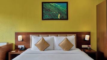 Habitación de hotel con cama, dos lámparas de noche, mesita de noche con teléfono y un cuadro en la pared.