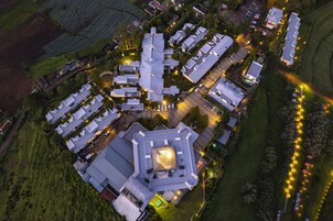An aerial view of a residential area with multiple detached houses, each with a distinct roof design, surrounded by greenery and a well-lit pathway.