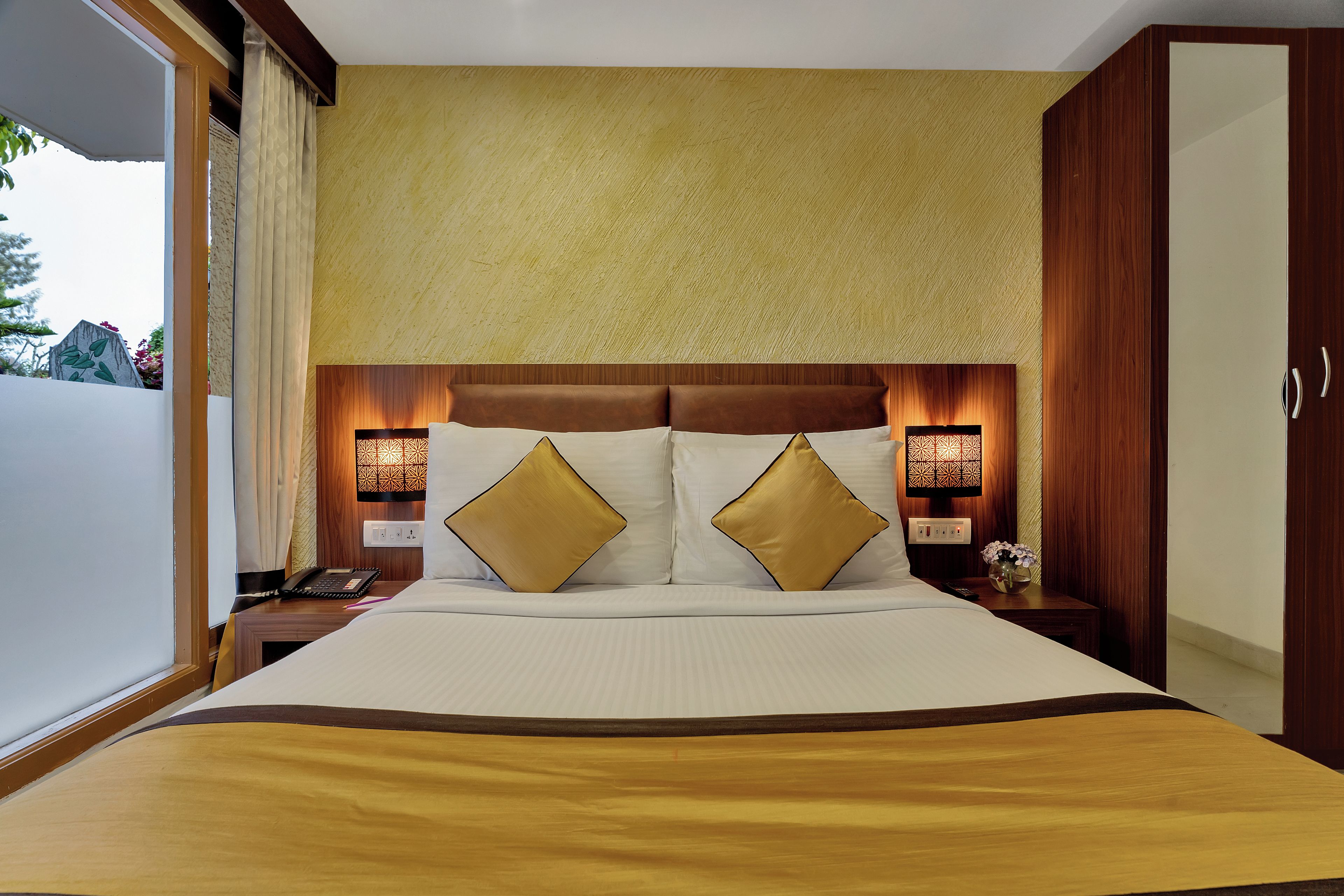 Ein Hotelzimmer mit einem großen Bett, zwei Nachttischlampen, einem Nachttisch und einem Kleiderschrank.