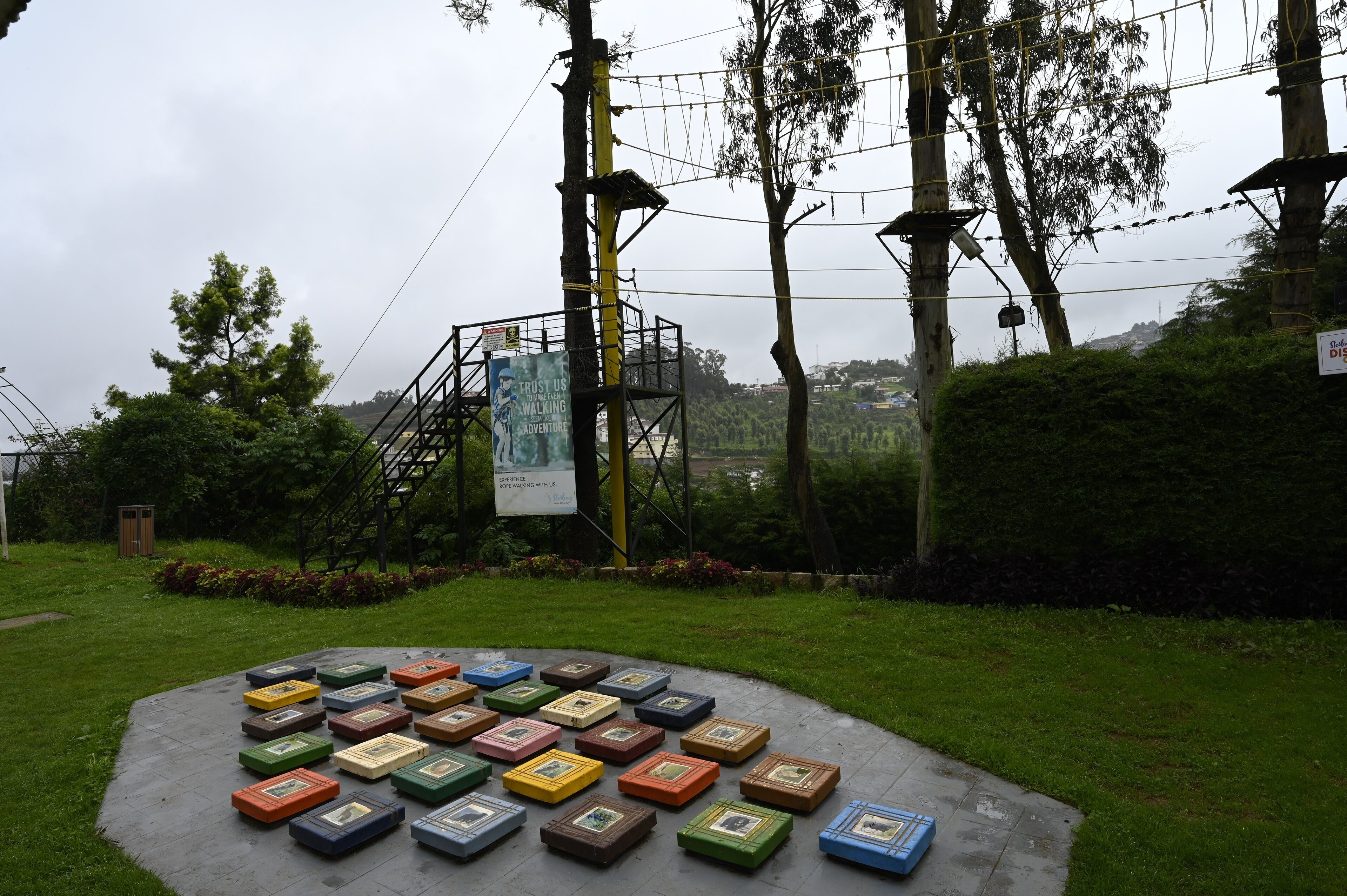 A circular arrangement of colorful boxes on a paved area, surrounded by greenery and a utility pole with a sign.