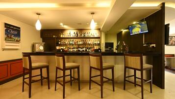 Een bar met een toonbank, diverse likeurflessen en drie houten stoelen.