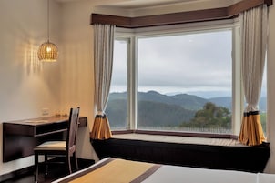 Habitación de hotel con un ventanal grande, un escritorio, una silla y una cama.
