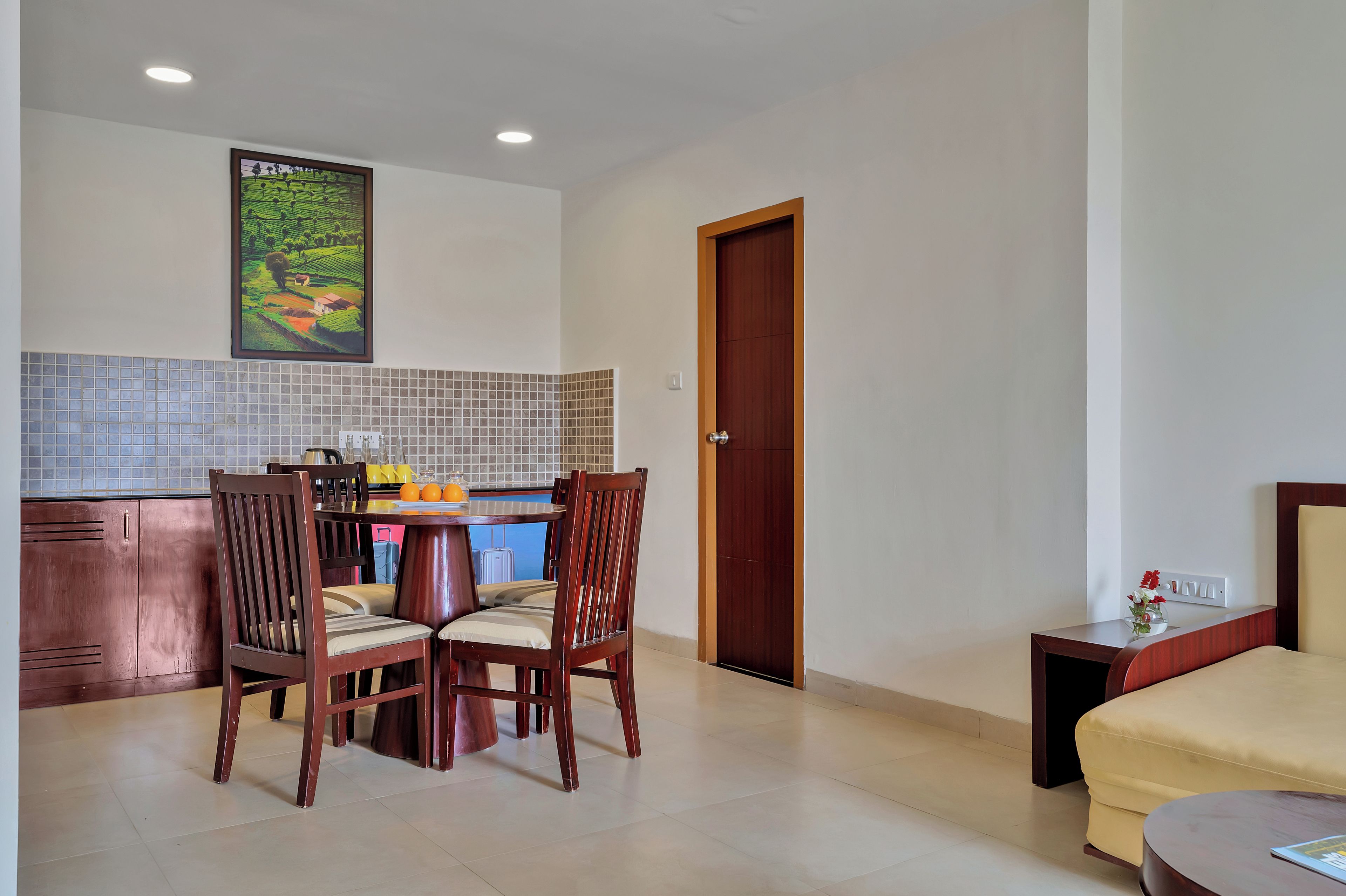 Habitación de hotel compacta con zona de comedor, puerta de madera y cama.
