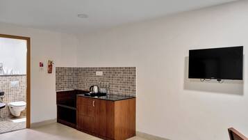 Una cocina compacta con salpicadero de azulejos, un armario de madera y encimera negra.