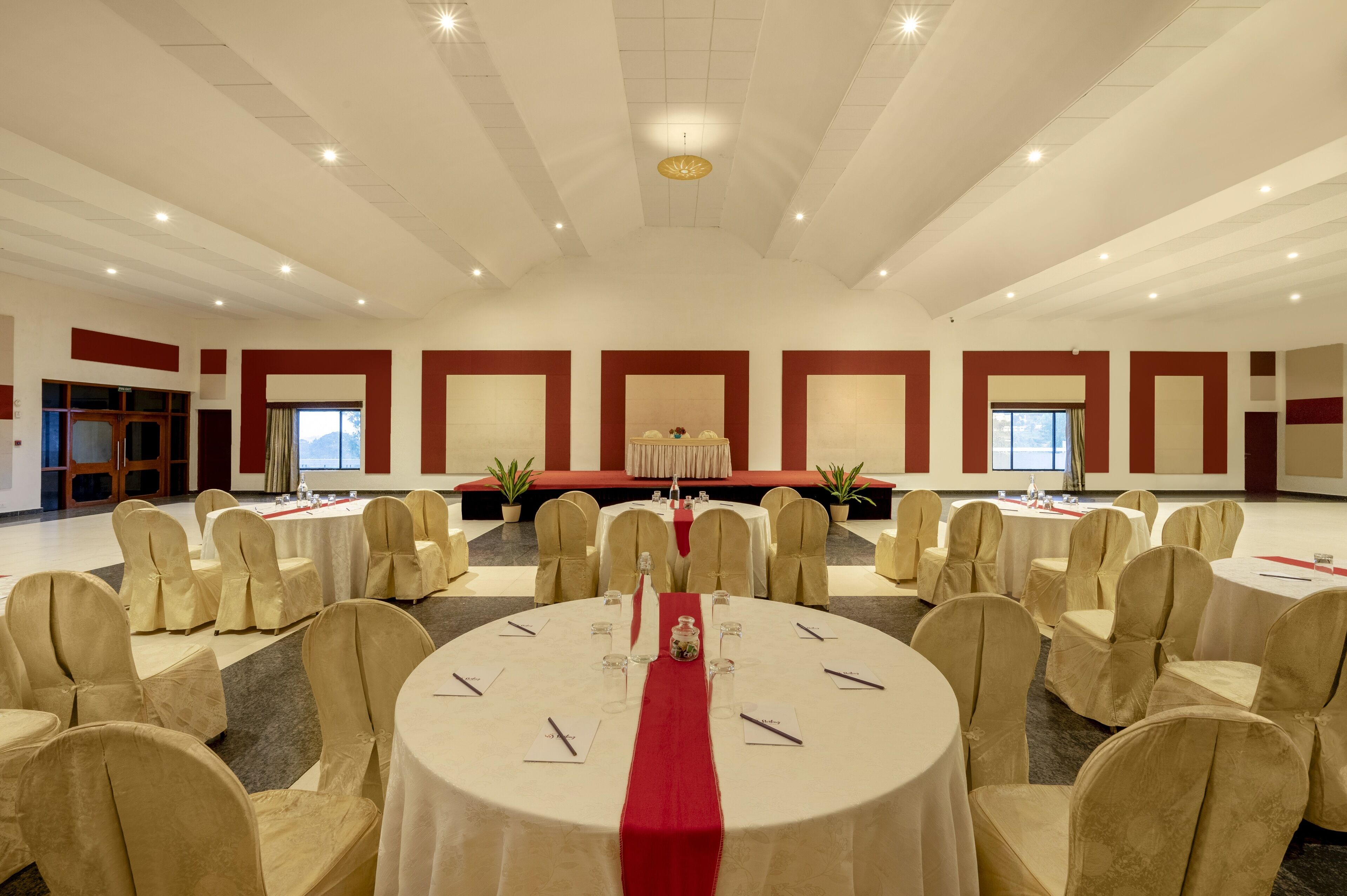 A large conference room with round tables, chairs, and a stage.