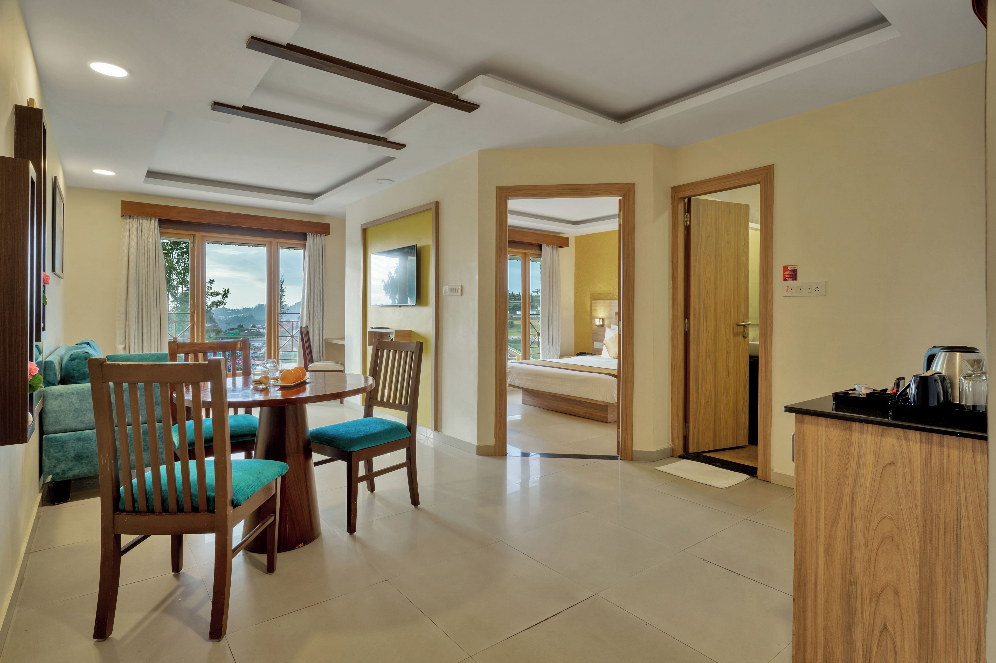 A hotel room with a dining area, a bed, and a kitchenette.