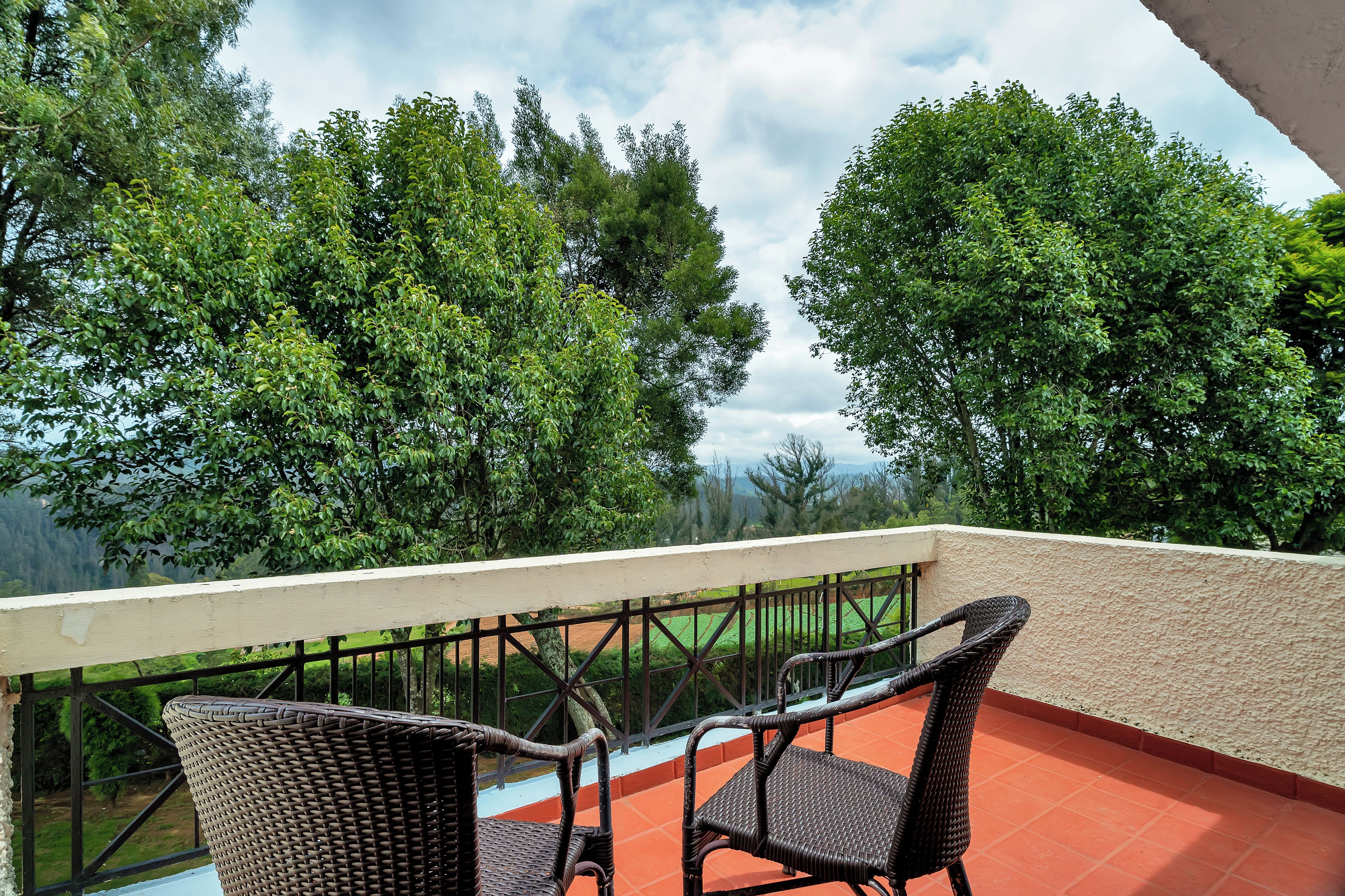 Ein Balkon mit Korbstühlen und Blick auf eine grüne Landschaft.