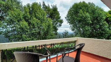 Ein Balkon mit Korbstühlen und Blick auf eine grüne Landschaft.