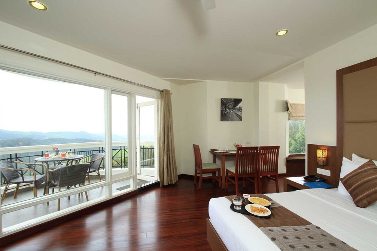 Una habitación de hotel con balcón, una mesa de comedor y una cama.