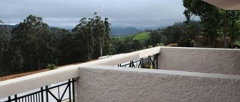 A balcony with a view of green hills and trees.
