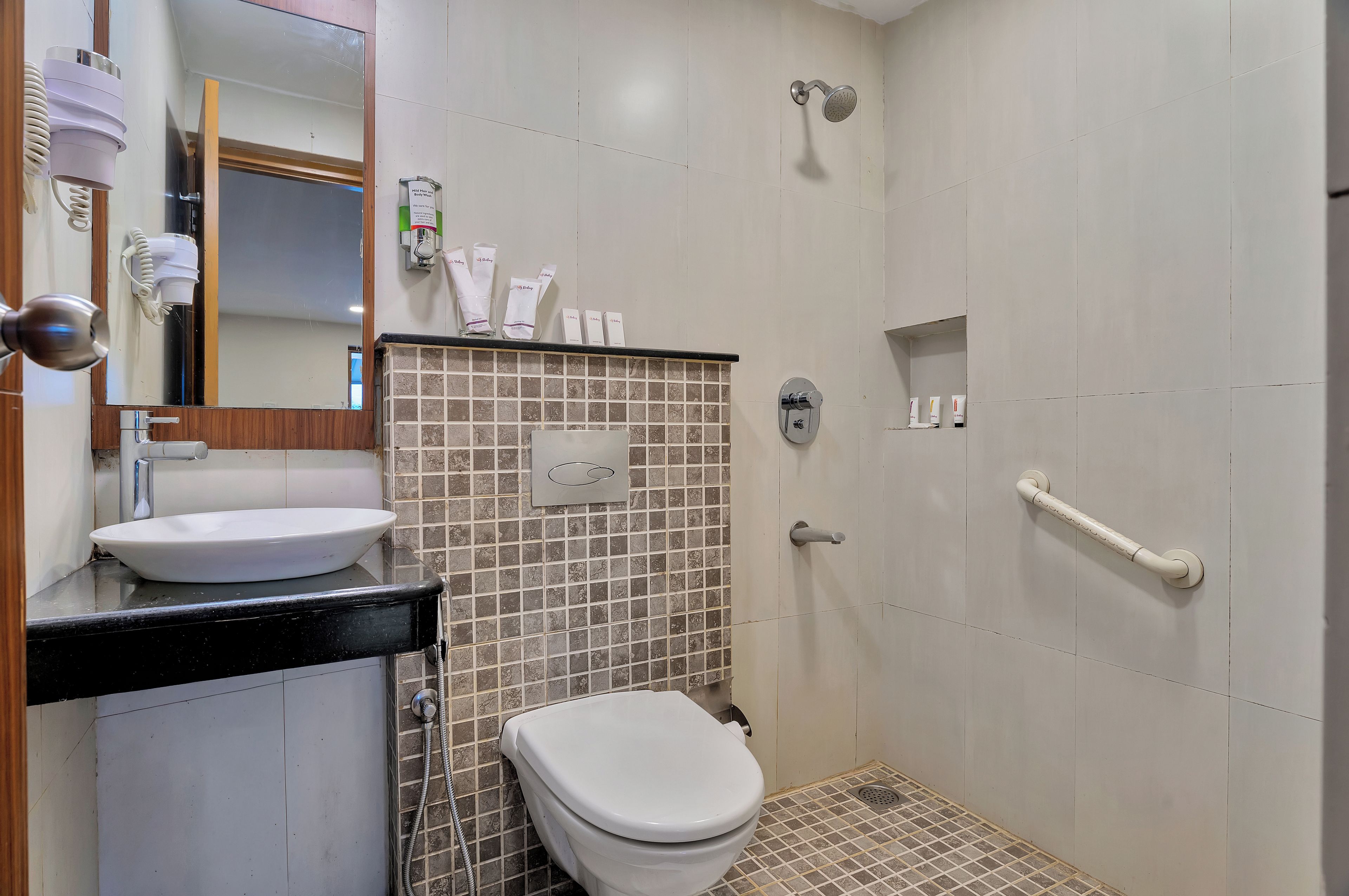 Un baño con inodoro blanco, lavamanos, ducha y espejo.