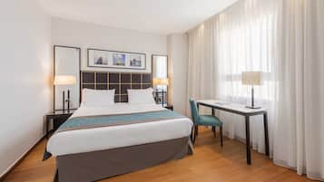 A hotel room with a bed, bedside tables, a desk, and a chair.