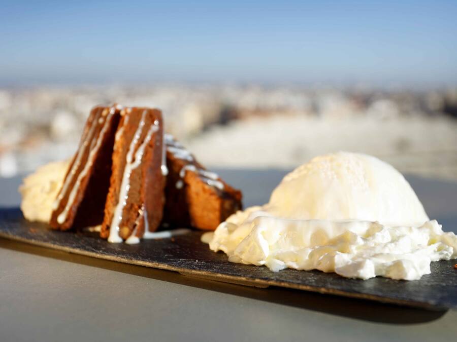 A dessert plate with a slice of cake and a scoop of ice cream on a dark slate.