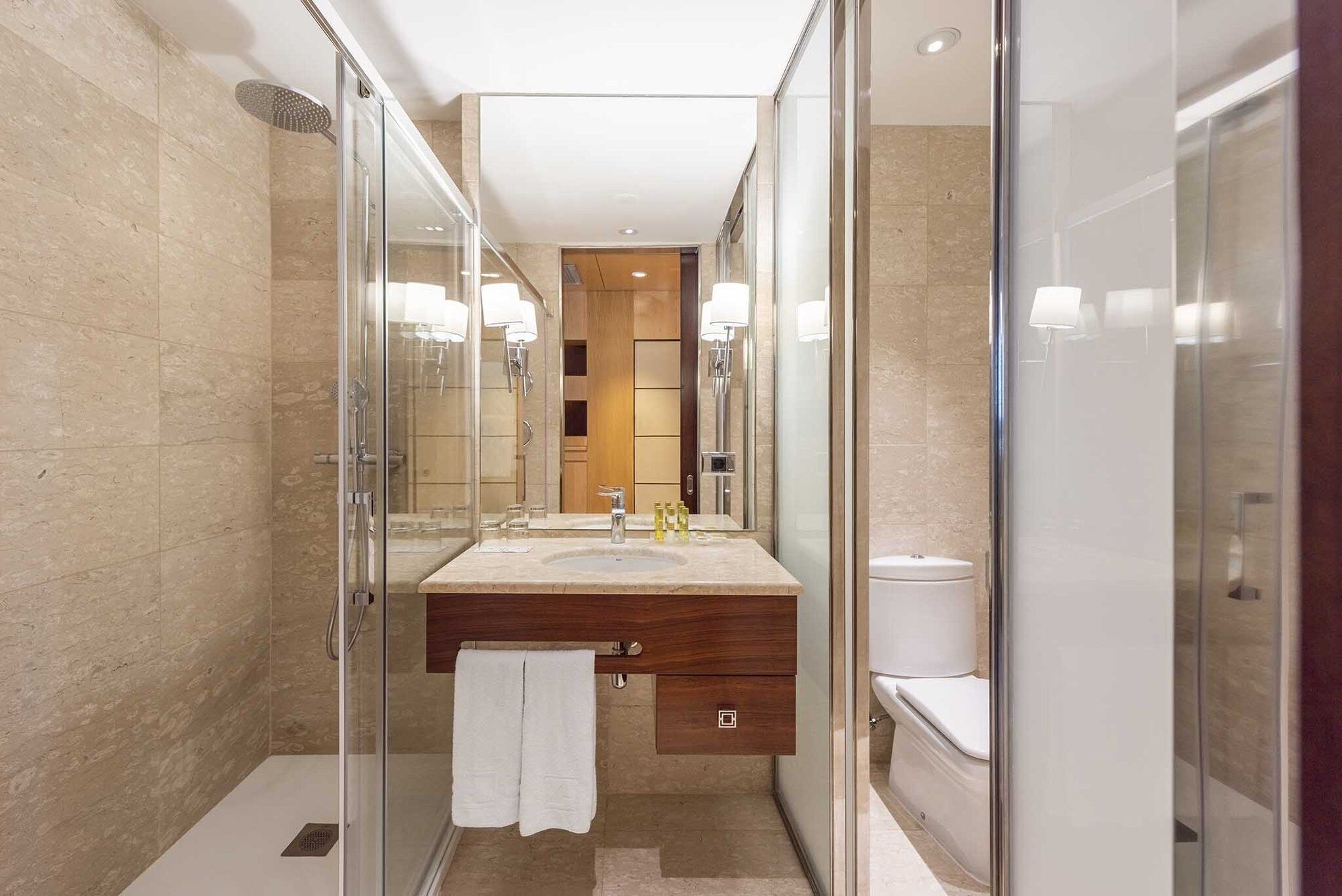 A modern bathroom with a glass-enclosed shower, a vanity with a sink, and a toilet.