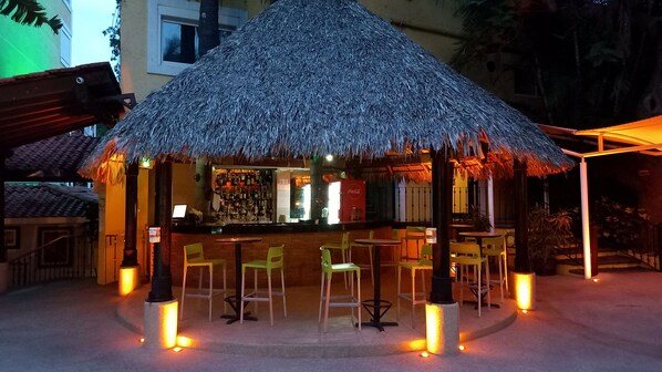 A bar area with a thatched roof, bar stools, and a counter with a Coca-Cola refrigerator. - Holiday Inn Cuernavaca by IHG (Cuernavaca)