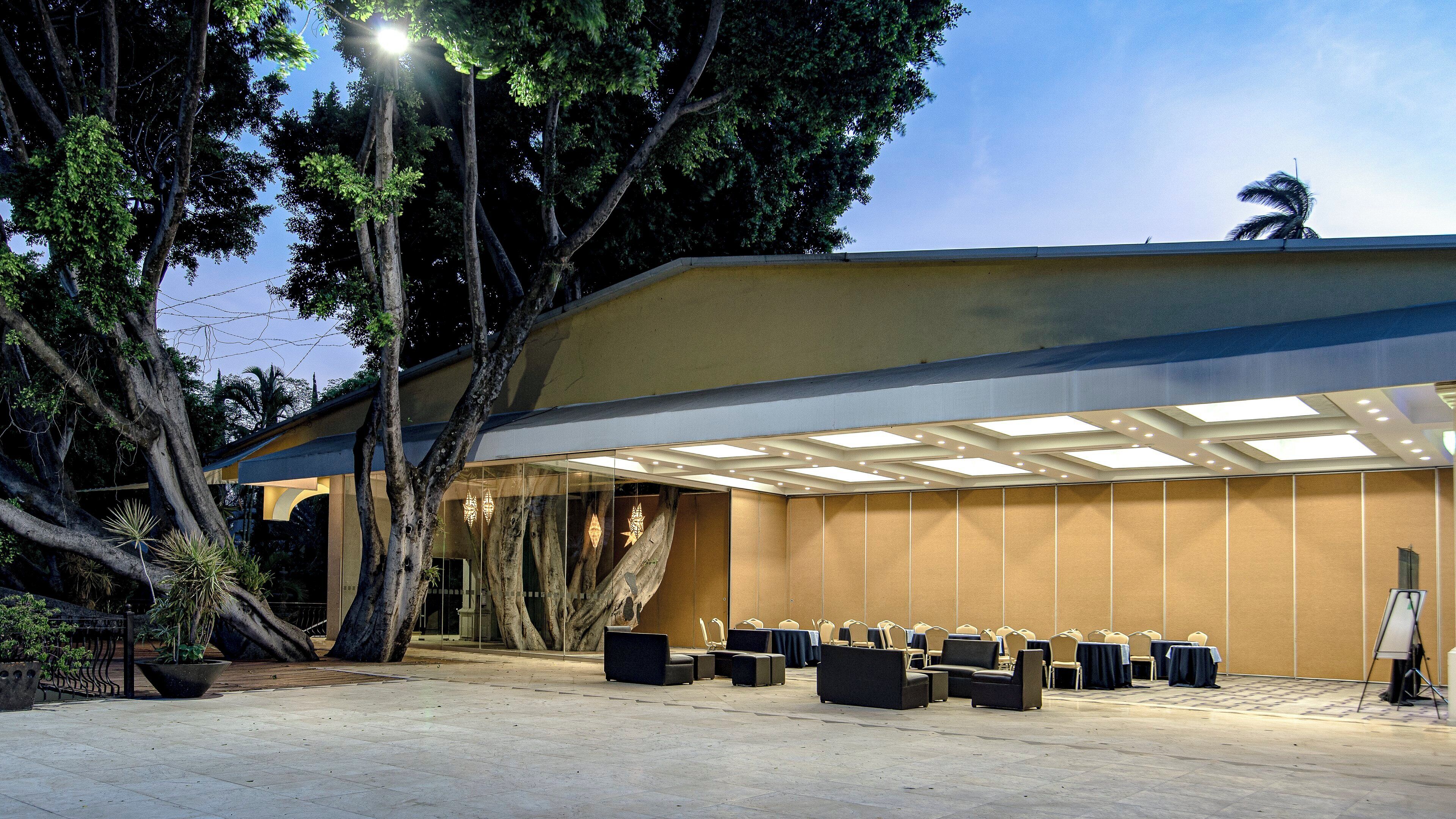 A conference room with a high ceiling, large windows, and a seating arrangement for events.
