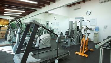 Un gimnasio con cintas de correr, máquinas de pesas y una bicicleta estática.