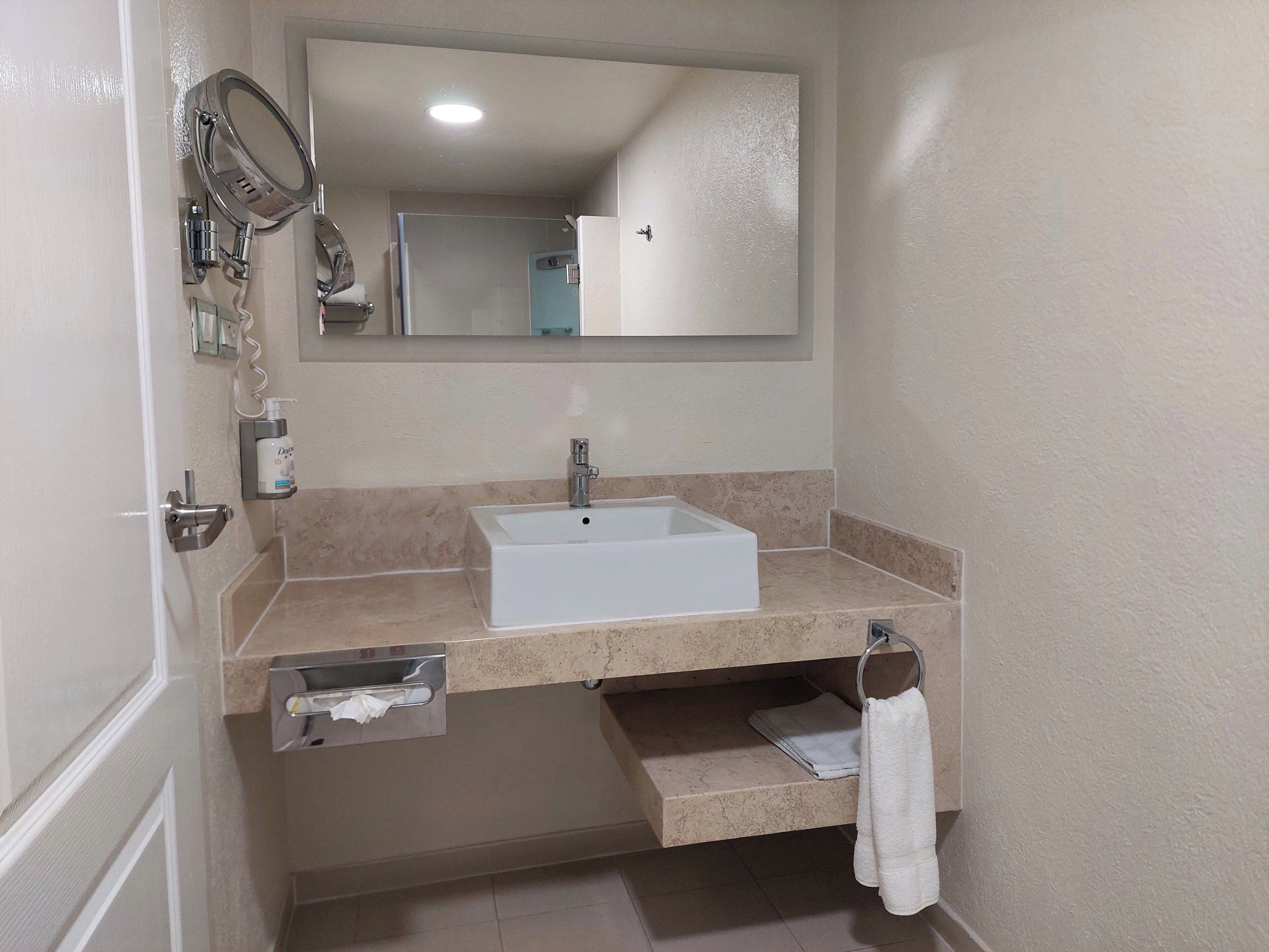 A bathroom with a white sink, a mirror, a towel rack, and a hand dryer.