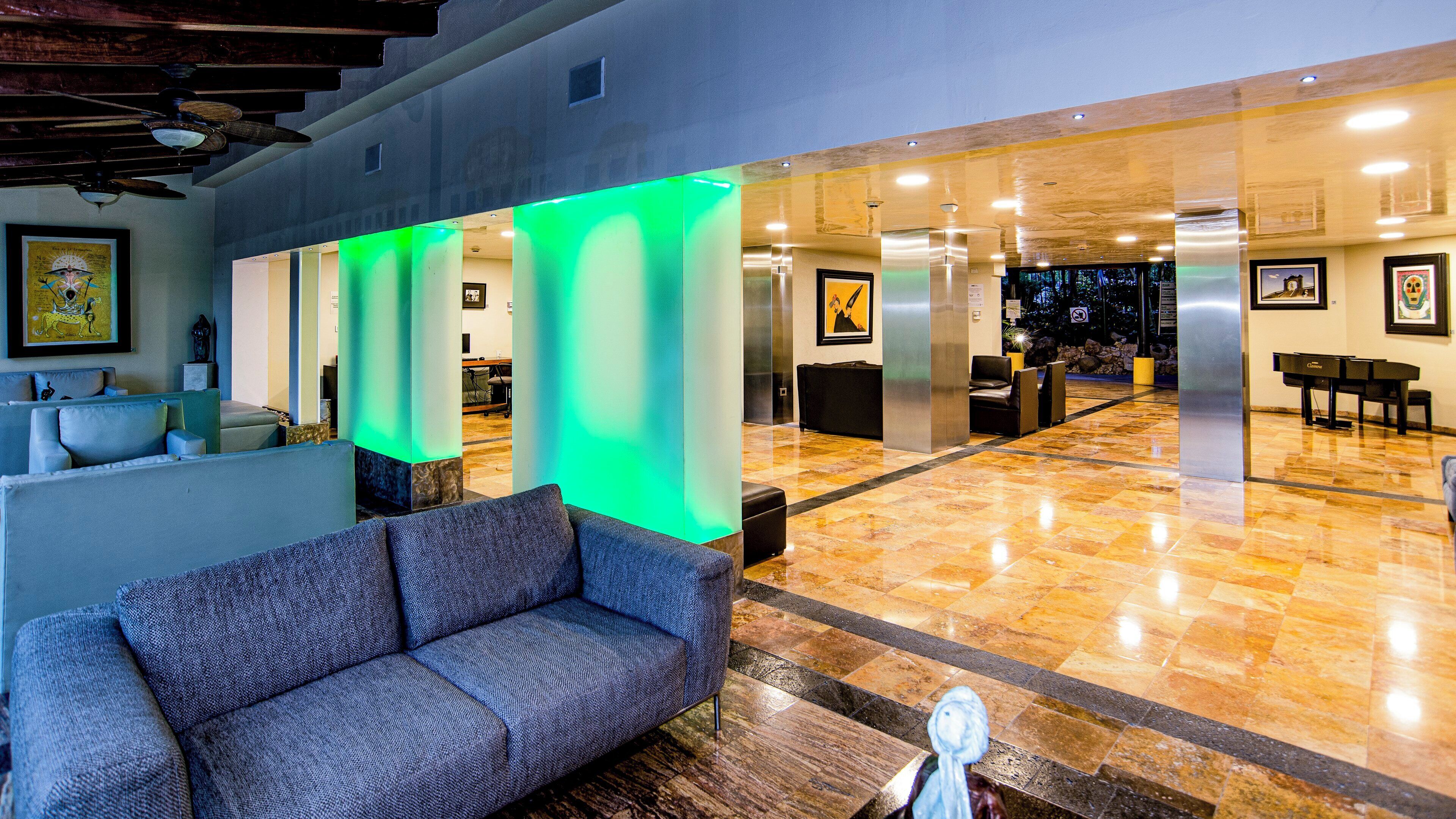 A lobby with a sofa, a piano, and a reception desk.
