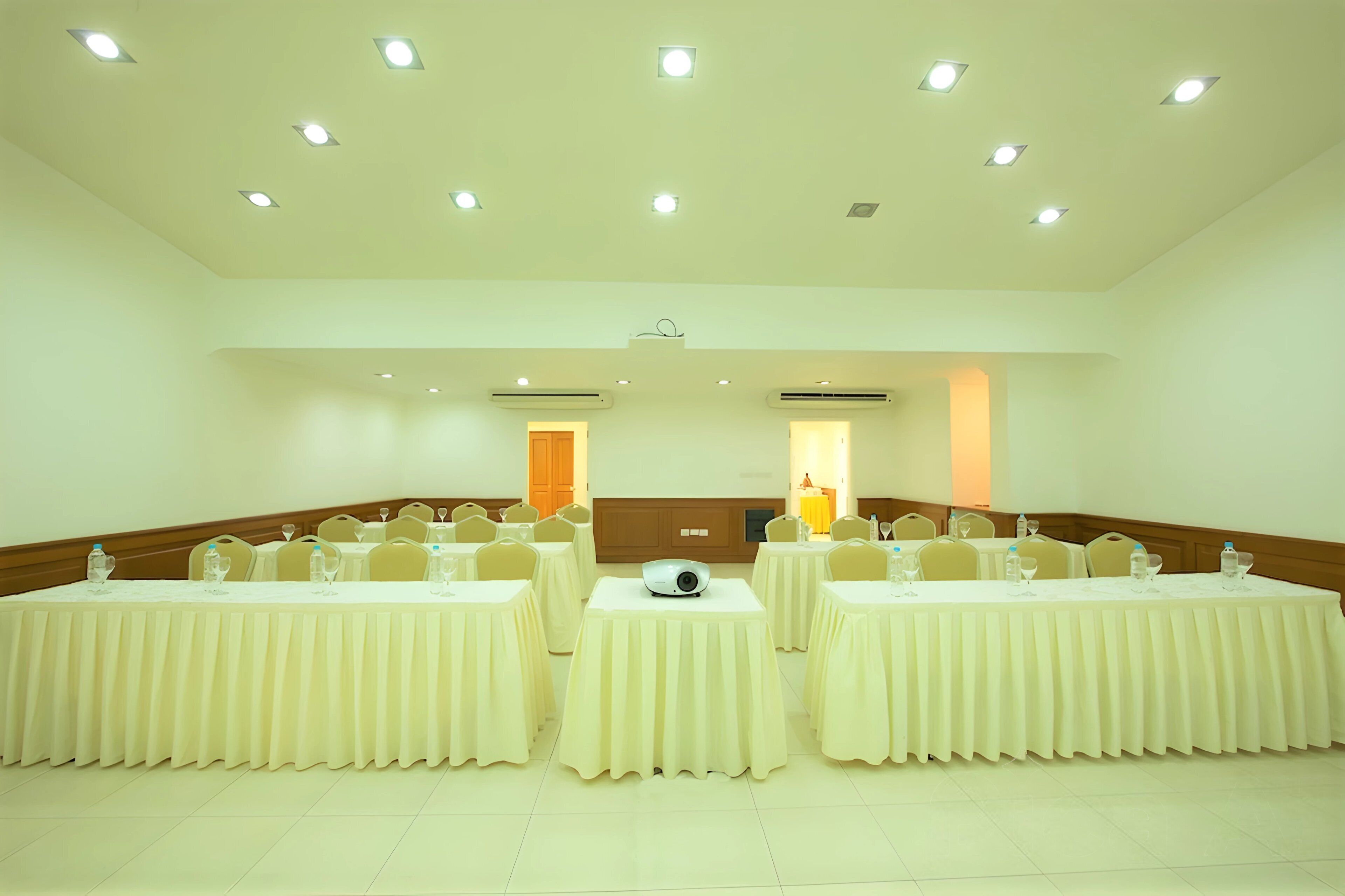 A conference room with tables set for meetings, equipped with projectors and water bottles.